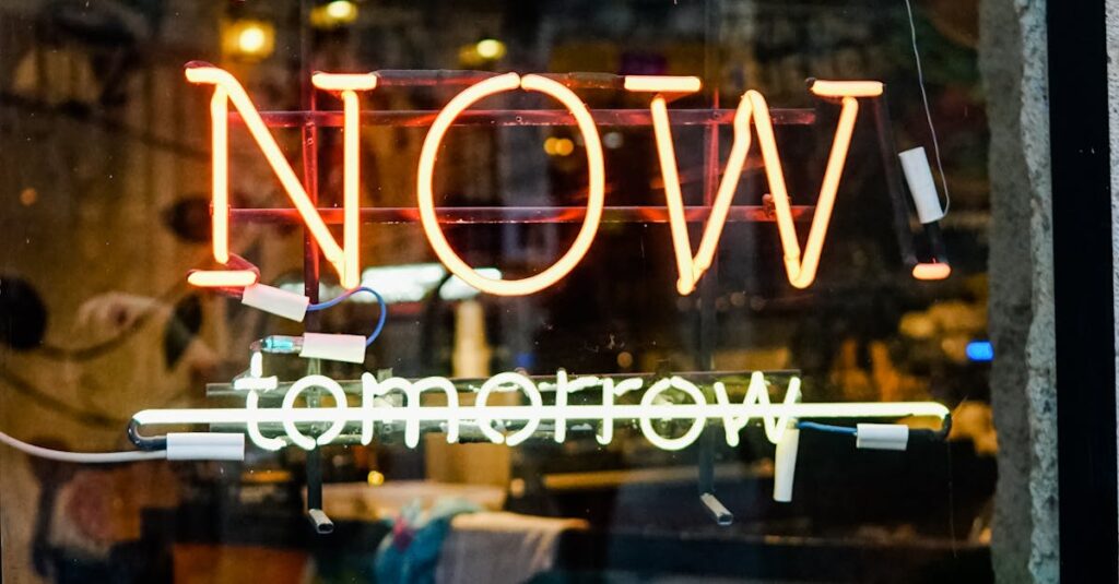 Colorful neon sign on a glass storefront with urban reflections and greenery.